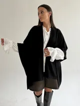 Ruana de tejido de punto trenzado en color crudo, con diseño abierto, corte holgado y mangas amplias tipo kimono.