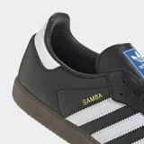 Championes Adidas Samba OG negros con las tres tiras laterales blancas, detalles en gamuza negra en la puntera y suela de goma marrón.