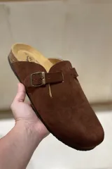 Zueco tipo mule de cuero color marrón chocolate, con tira ajustable y hebilla metálica. Presenta plantilla anatómica con memory cushion y suela de corcho y goma.