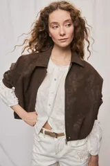 Campera marrón de poliuretano con acabado texturizado, silueta relajada, cuello camisero, cierre frontal, hombros caídos y mangas amplias con efecto abombado.
