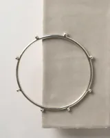 Brazalete rígido de plata 925, tipo esclava, decorado con una secuencia de pequeñas esferas a lo largo de su estructura.