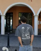 Remera oversize negra con diseño gráfico en la espalda que incluye la inscripción "Kaboa Radio" y un personaje ilustrado, de corte amplio y mangas cortas.