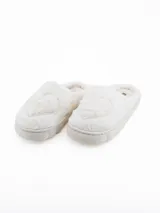 Pantuflas de peluche color blanco con diseño de corazón en relieve en la parte superior y suela de plataforma acolchada.