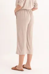Pantalon palazzo de corte recto y tiro alto, confeccionado en lino color beige, con cierre frontal y bolsillos laterales.