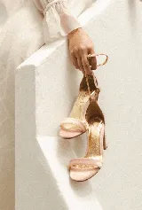 Sandalias de fiesta color rosa pálido, con una tira delgada sobre los dedos y pulsera al tobillo. El interior es dorado y el taco mide 8cm.