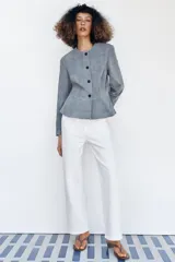 Chaqueta de cuero gamuzado color gris, con cuello redondo, manga larga, cierre frontal con botones oscuros y bajo con detalle peplum.