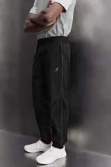 Pantalón jogger negro de corte regular, confeccionado en tejido técnico con algodón. Presenta cintura elástica ajustable con cordón interior, bolsillos laterales y puños elásticos en los tobillos. Posee un pequeño logo estampado en contraste en la pierna derecha.