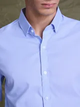 Camisa de vestir manga larga en color celeste, con cuello clásico y cierre frontal de botones. Presenta un corte entallado y puños con botones.