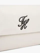 Cartera shoulder de Tommy Hilfiger en color beige, con solapa y correa corta ajustable de color negro. Presenta el monograma "TH" en relieve negro en el frente y herrajes metálicos plateados.