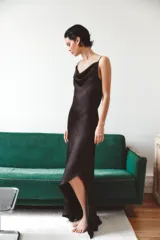 Vestido largo de tejido satinado con escote drapeado y tirantes finos. Presenta un diseño fluido con bajo asimétrico y cierre lateral con cremallera.