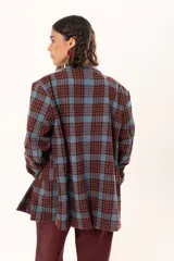 Blazer de corte oversize con estampado de cuadros en tonos azul, bordó y marrón. Presenta solapas clásicas, bolsillos con solapa en el frente y cierre frontal con botones.