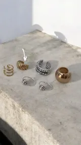 Ear cuff de diseño minimalista y forma esférica, acabado en tono dorado brillante.