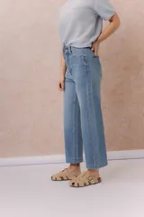 Jean de denim celeste con lavado claro, corte recto y tiro medio-alto, con diseño de cinco bolsillos y cierre frontal con botón y cremallera.