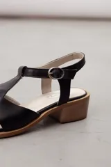Sandalias tipo pescador de cuero negro con tiras entrelazadas, taco bajo cuadrado y tira ajustable con hebilla en el tobillo.