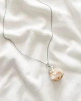 Collar con cadena plateada y dije de piedra color naranja.