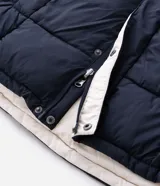 Campera puffer de hombre reversible, con diseño acolchado, cuello alto, capucha y cierre frontal.