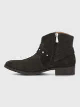 Bota corta de gamuza color marrón oscuro, con diseño de correa decorativa con tachas metálicas y hebilla lateral. Cuenta con cierre lateral para un ajuste cómodo y suela de goma.