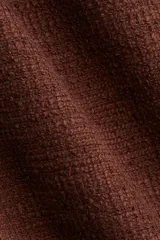 Pollera corta de tejido bouclé color marrón oscuro, de tiro alto y corte recto, con bajo desflecado.