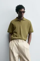 Polo de manga corta color verde oliva, con cuello solapa y abertura frontal tipo polo. Presenta una textura acanalada vertical y un calce regular.