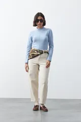 Polera de tejido de punto color celeste, con cuello alto y textura de pequeños puntos en relieve formando una cuadrícula en el frente y las mangas. De corte ajustado y manga larga.