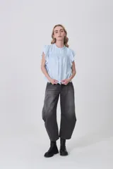 Blusa celeste de viscosa con diseño holgado, cuello a la base con detalle de volados, mangas cortas con volados y detalle de punto smock en el pecho.