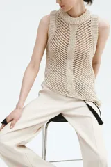 Pantalón sastrero de tiro alto en color beige, con perneras amplias y raya marcada en la parte delantera y trasera. Cuenta con cierre de cremallera, botón oculto y corchete, además de bolsillos decorativos insertados.