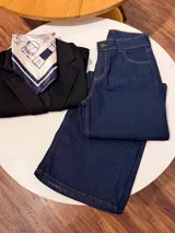 Pantalón de jean corte wide leg, color azul oscuro, con costuras en hilo color camel y cierre frontal con botón metálico.