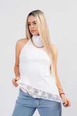 Polera de seda con lycra color blanco, de cuello alto y espalda descubierta. Presenta un diseño asimétrico en la parte inferior con un detalle de encaje sutil en el ruedo.