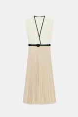 Vestido midi bicolor con parte superior blanca de escote en V cruzado con ribete negro y falda plisada en color tostado. Cuenta con mangas sisa, cintura elástica y un cinturón negro tipo reptil con hebilla ovalada.