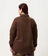 Camisa tipo overshirt de Ashua confeccionada en suede sintético color marrón. Presenta cuello clásico, cierre frontal con botones, mangas largas con puños abotonados y dos bolsillos frontales aplicados.
