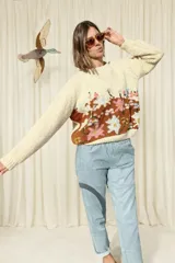 Sweater de lana merino en color marfil, confeccionado a mano con diseño floral multicolor y marrón en la parte frontal. Cuenta con cuello redondo a la base y mangas largas con textura en punto arroz.