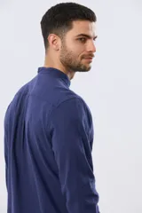 Camisa de lino y algodón color beige, de manga larga, con cuello mao y cierre frontal con botones. Presenta un pequeño bordado al tono en el pecho.