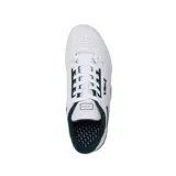 Championes Lacoste modelo M89, de diseño urbano y deportivo. Presentan una base de cuero blanco con perforaciones laterales para mayor ventilación, detalles en color verde oscuro en el cuello, logo de la marca y refuerzos, y una suela de goma gris con diseño texturizado.
