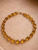 Collar de piedras semipreciosas facetadas en tono ámbar, con cierre metálico con baño de oro 18k.