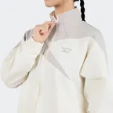Campera deportiva Reebok de corte holgado, color beige con detalles en gris. Presenta cierre frontal con cremallera, cuello alto, mangas largas con puños elásticos y logo bordado en el pecho.