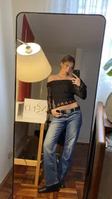 Top negro de encaje con escote bardot y mangas largas acampanadas.