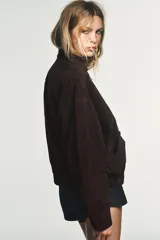 Cazadora tipo bomber de Zara confeccionada en piel de ante 100%. Presenta cuello redondo, cierre frontal con cremallera metálica, bolsillos delanteros con solapa y bajo con acabado elástico.