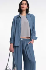 Camisa oversized color azul, con abotonadura frontal y en las mangas. Presenta un corte vertical en la espalda con lazos decorativos.