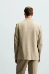 Blazer color beige de corte relaxed fit, confeccionada en tejido con viscosa. Tiene cuello con solapas de muesca, manga larga con puño abotonado, bolsillos frontales de plastrón, medio forro interior, aberturas en la espalda y cierre frontal con botones. Presenta un efecto lavado.