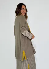 Saco azul de tejido de punto con rayas horizontales en tonos grises y detalles en rojo. Tiene corte holgado, mangas 3/4 y bolsillos laterales.