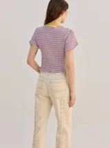 Remera baby-tee a rayas verde y blanca con cuello redondo rojo y gráfico impreso en la parte delantera, de manga corta y textura fruncida.