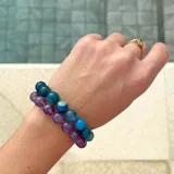 Pulsera de cuentas esféricas de ágata azul de 10 mm, unidas mediante nudos de hilo azul. Presenta cierre de mosquetón y terminales con baño de oro.