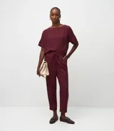 Pantalón de vestir femenino color marrón oscuro, de corte fluido y tiro medio/alto, con cintura elástica ajustable mediante cordón. Presenta bolsillos laterales y cierre frontal.