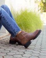 Botinetas de cuero color marrón con diseño combinado en cuero liso y gamuza. Presentan suela track de goma negra con taco cuadrado y tirador en la parte trasera.