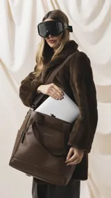 Cartera tipo tote marrón de diseño práctico y versátil, confeccionada en símil cuero con textura granulada. Cuenta con asas cortas fijas, bolsillos exteriores con cierre al frente y atrás, y bolsillos laterales abiertos. Su interior es amplio e incluye bolsillos organizadores. Viene con una correa ajustable y desmontable.