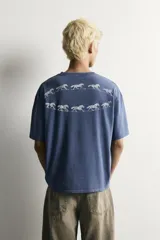 Remera boxy fit azul con efecto lavado, cuello redondo y manga corta, con estampa en el pecho.
