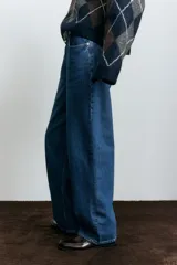 Jean de corte baggy con tiro alto, confeccionado en denim de algodón. Presenta diseño de cinco bolsillos, cierre frontal con botón y piernas con volumen en la zona de la cadera que se estrechan ligeramente hacia el bajo.