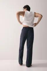 Pantalón de popelina de algodón azul marino con finas rayas verticales blancas. Presenta cintura elástica con cordón ajustable y bolsillos laterales.