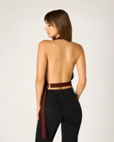 Top halter de satén color borgoña con escote drapeado, espalda descubierta y detalle de argolla metálica en el hombro.