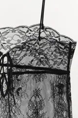 Top de encaje semitransparente con escote recto, tirantes finos y cierre posterior con lazadas.